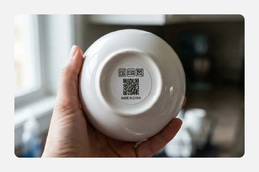 תחתית של קערת קרמיקה לבנה עם מדבקת ברקוד QR והוראות שטיפה במדיח
