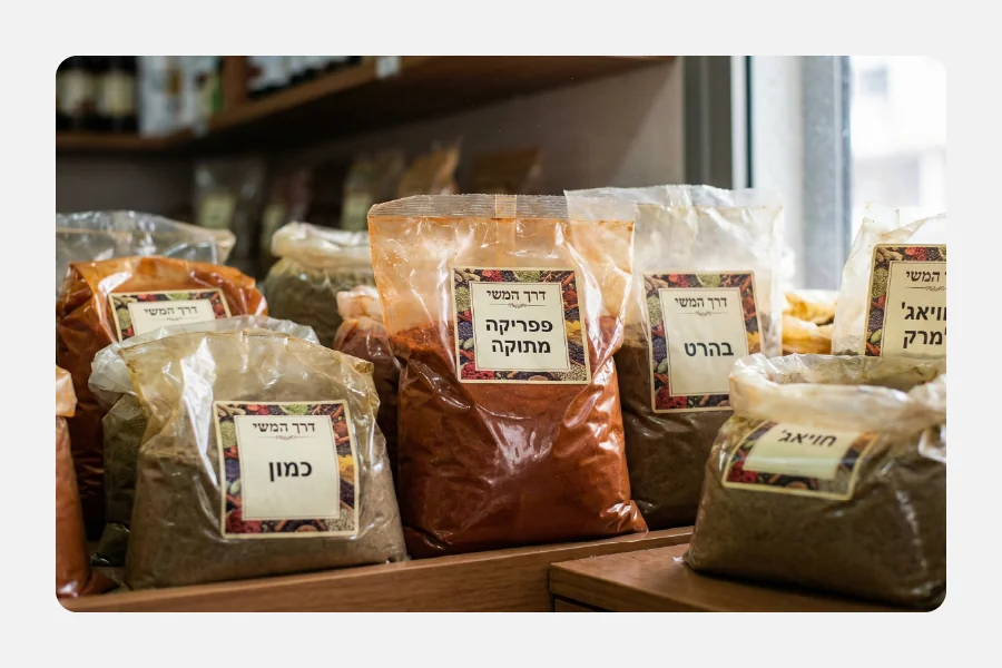 שקיות תבלינים שקופות על מדף עם מדבקות מיתוג מרובעות וכיתוב בעברית