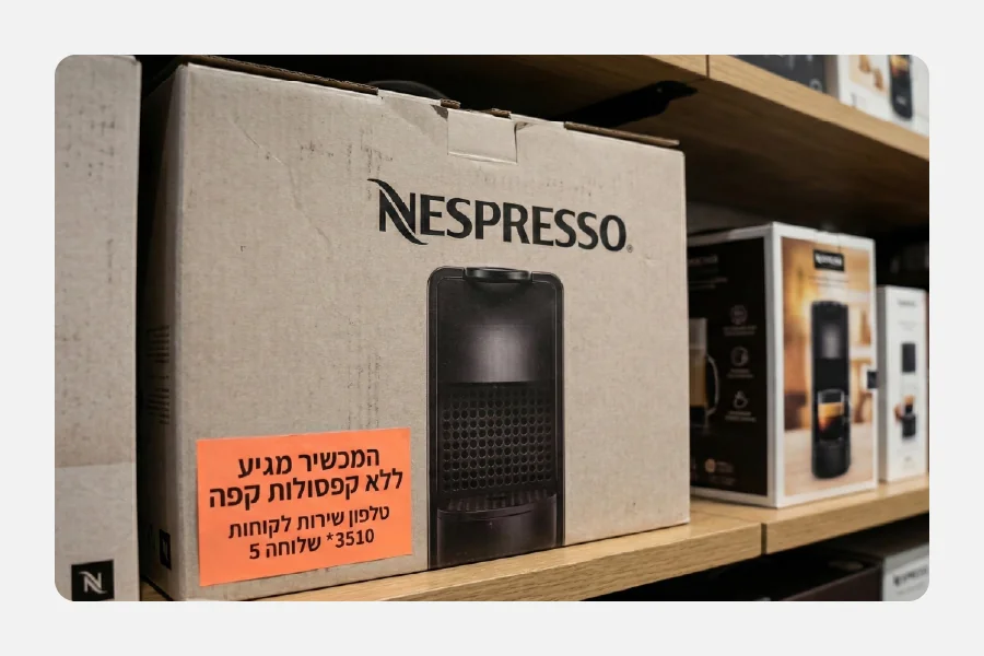ארגז קרטון של מכונת נספרסו עם מדבקה כתומה זוהרת גדולה ועליה כיתוב אזהרה לגבי תכולת המארז