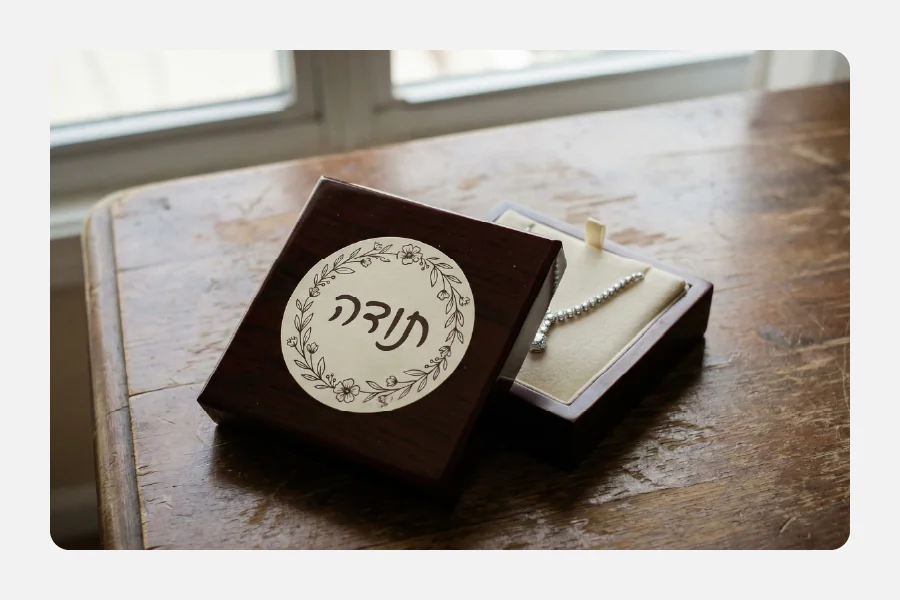 קופסת תכשיטים מעץ עם שרשרת ומדבקת תודה עגולה עם עיטור פרחים על המכסה