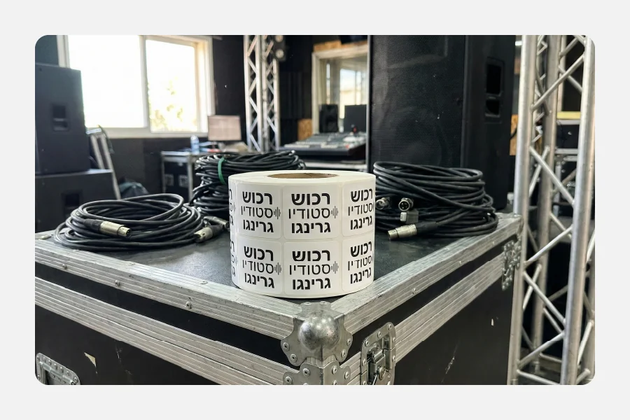 גליל מדבקות ויניל מרובעות עם הכיתוב "רכוש סטודיו גרינגו" על ארגז ציוד טכני (Flight Case) בסביבת סטודיו.